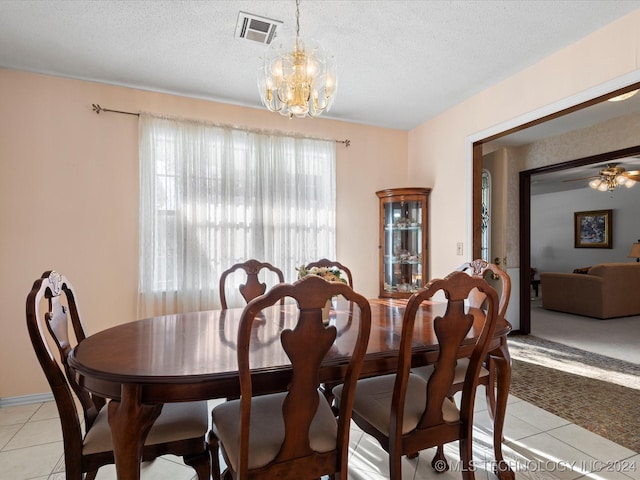 tiled dining room featuring ceiling fan with notable chandelier and a textured ceiling