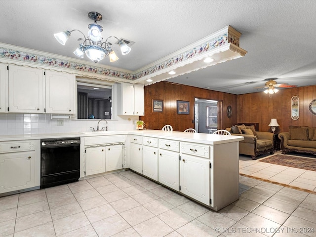 kitchen featuring black dishwasher, backsplash, kitchen peninsula, wooden walls, and white cabinets