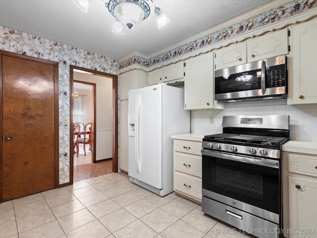 kitchen featuring appliances with stainless steel finishes, backsplash, a textured ceiling, and light tile patterned flooring