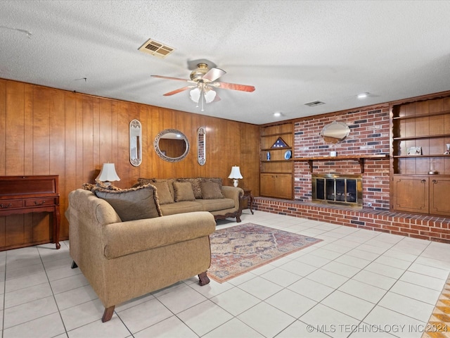 living room featuring a textured ceiling, ceiling fan, light tile patterned floors, built in features, and wood walls