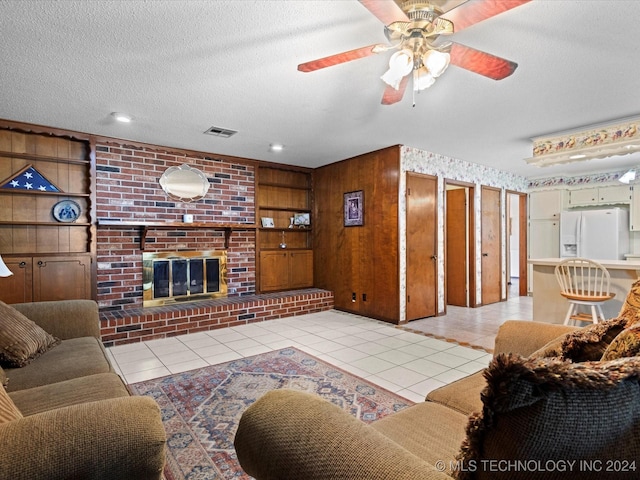 tiled living room with built in features, a textured ceiling, a brick fireplace, and ceiling fan