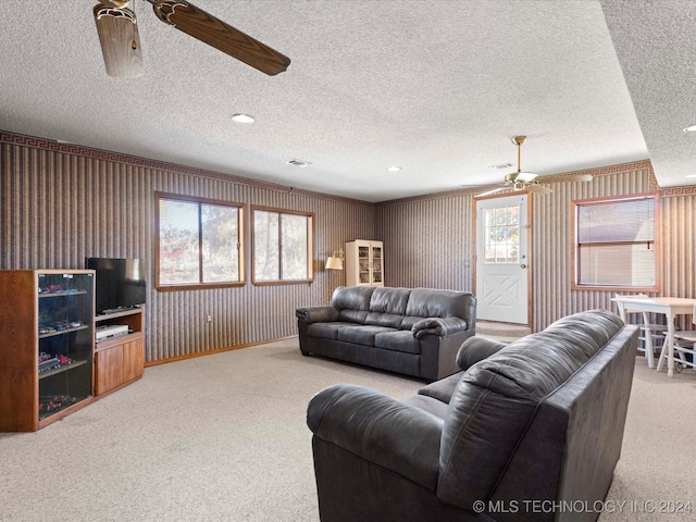 carpeted living room with a textured ceiling, ceiling fan, and a healthy amount of sunlight