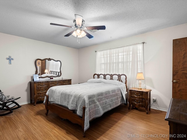 bedroom with a textured ceiling, light wood-type flooring, and ceiling fan