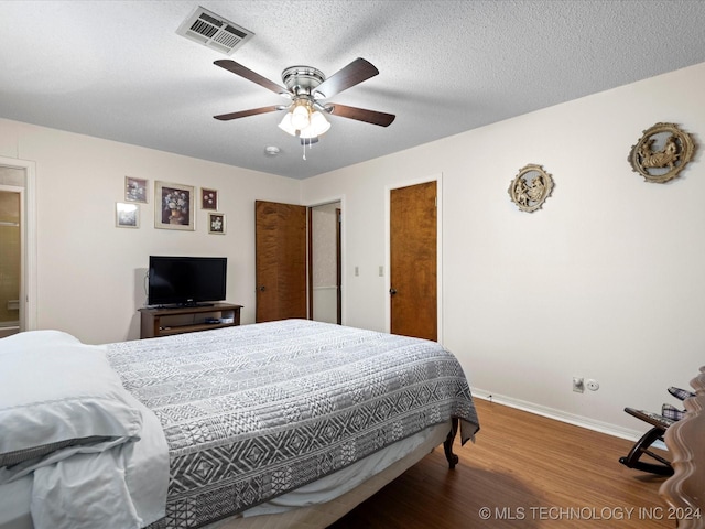 bedroom with hardwood / wood-style flooring, ceiling fan, and a textured ceiling