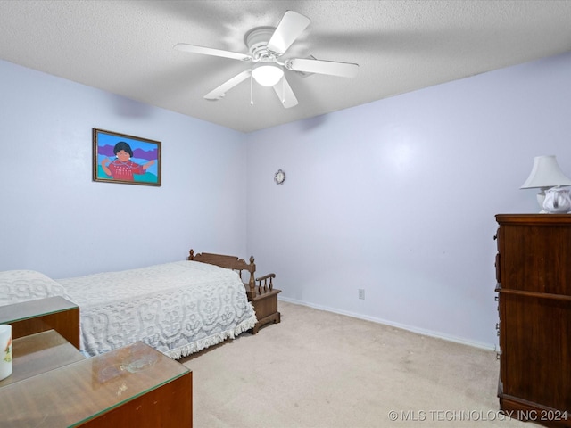 bedroom featuring ceiling fan, light carpet, and a textured ceiling