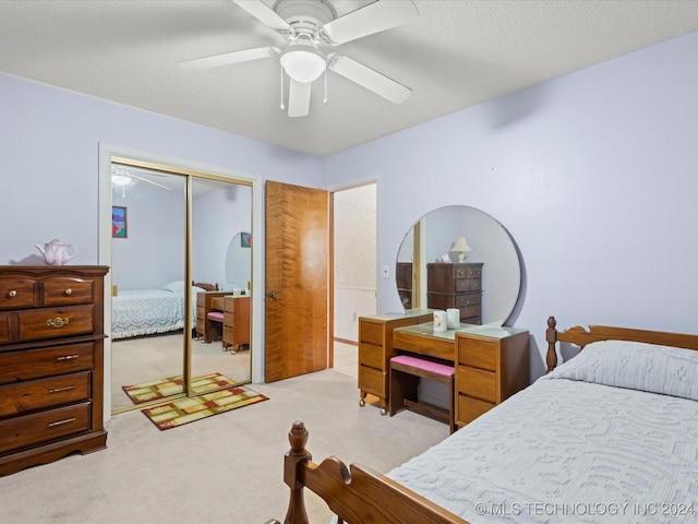 bedroom featuring a textured ceiling, a closet, ceiling fan, and light colored carpet