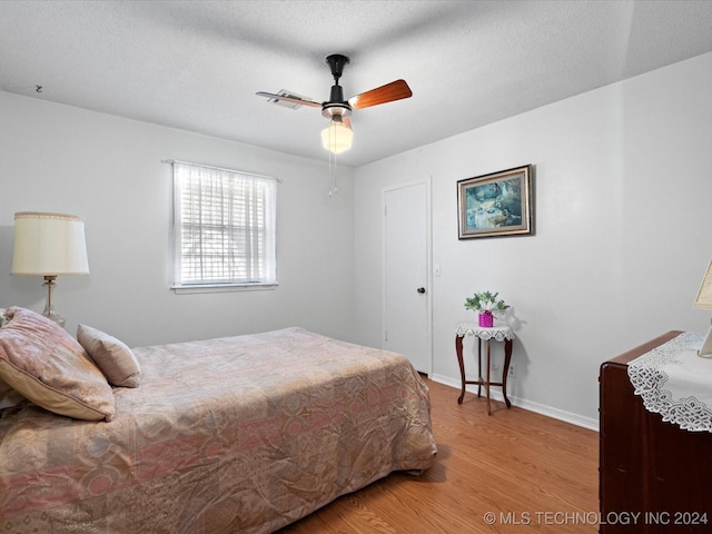 bedroom featuring ceiling fan, light hardwood / wood-style flooring, and a textured ceiling