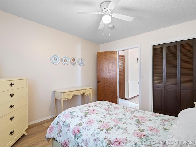 bedroom with a textured ceiling, a closet, light hardwood / wood-style flooring, and ceiling fan