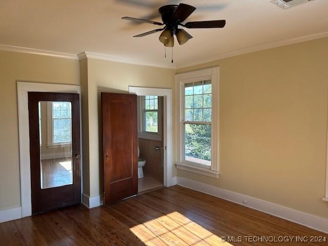 unfurnished bedroom featuring ceiling fan, dark hardwood / wood-style flooring, crown molding, and ensuite bath