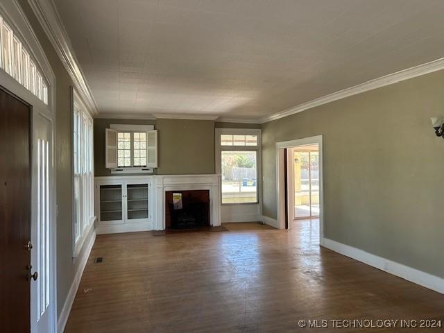 unfurnished living room featuring wood-type flooring and ornamental molding