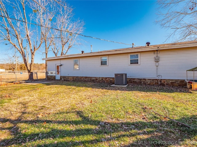 back of property with central AC and a lawn