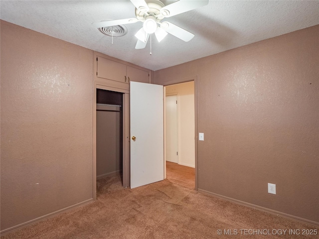 unfurnished bedroom featuring light carpet, a textured ceiling, a closet, and ceiling fan