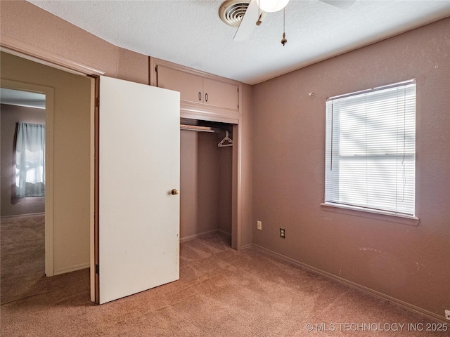 unfurnished bedroom with ceiling fan, light colored carpet, a closet, and a textured ceiling