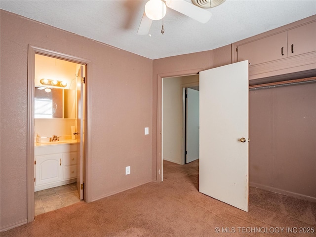 unfurnished bedroom with sink, ceiling fan, ensuite bathroom, light carpet, and a closet