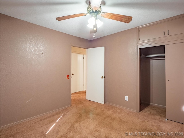 unfurnished bedroom with light carpet, a textured ceiling, a closet, and ceiling fan