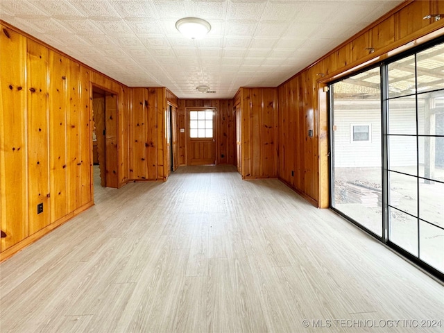 unfurnished room with light hardwood / wood-style floors and wooden walls