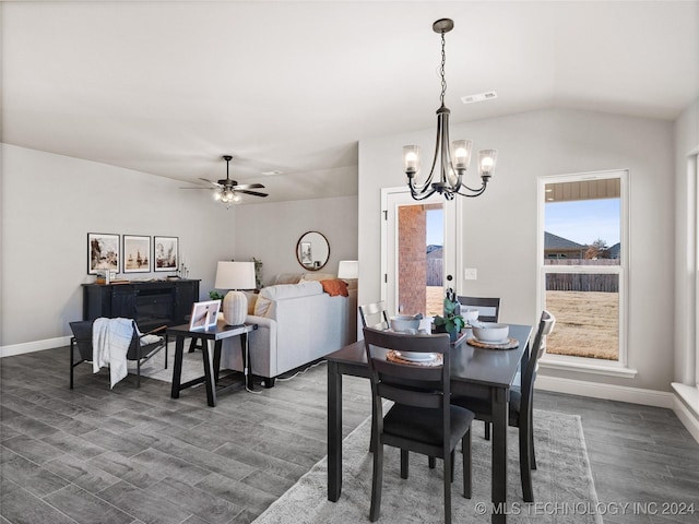 dining space featuring ceiling fan with notable chandelier, dark wood-type flooring, and vaulted ceiling