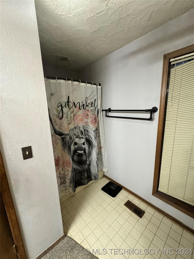 bathroom featuring a shower with curtain, a textured ceiling, and tile patterned floors