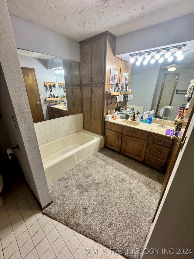 bathroom featuring vanity, a textured ceiling, tile patterned floors, and a bathtub