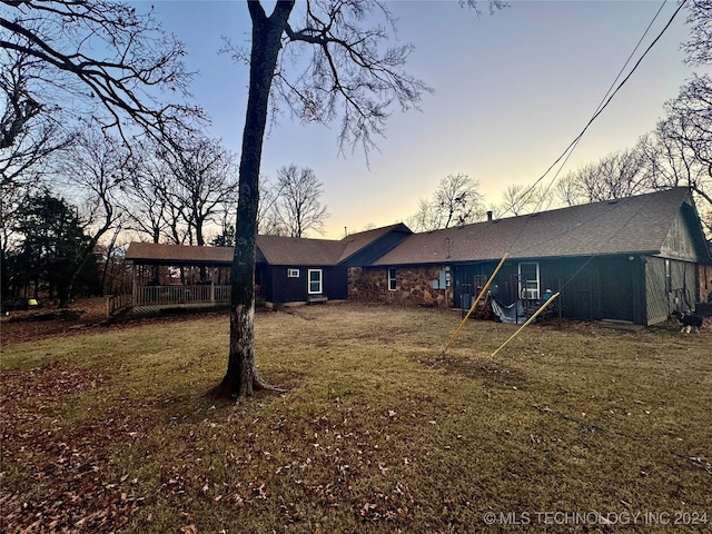 back house at dusk with a lawn