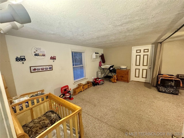 bedroom with a wall mounted AC, a textured ceiling, and a nursery area