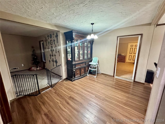 dining area featuring hardwood / wood-style floors, a textured ceiling, and an inviting chandelier