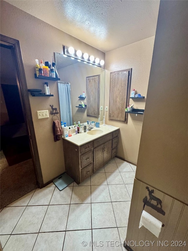 bathroom with tile patterned flooring, a textured ceiling, and vanity