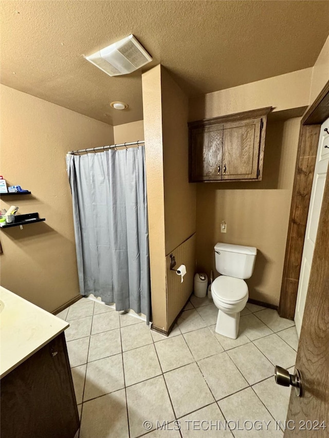 bathroom featuring tile patterned floors, vanity, a textured ceiling, and toilet