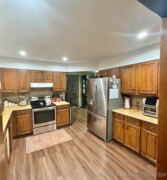 7750 River Ridge Rd, Muskogee, OK 74403 - kitchen featuring appliances with stainless steel finishes, under cabinet range hood, brown cabinets, light wood-style flooring, and recessed lighting