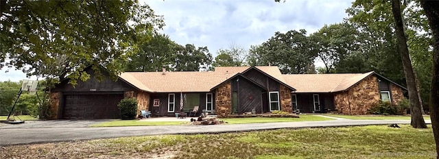 7750 River Ridge Rd, Muskogee, OK 74403 - view of front facade with stone siding, asphalt driveway, a front lawn, and an attached garage