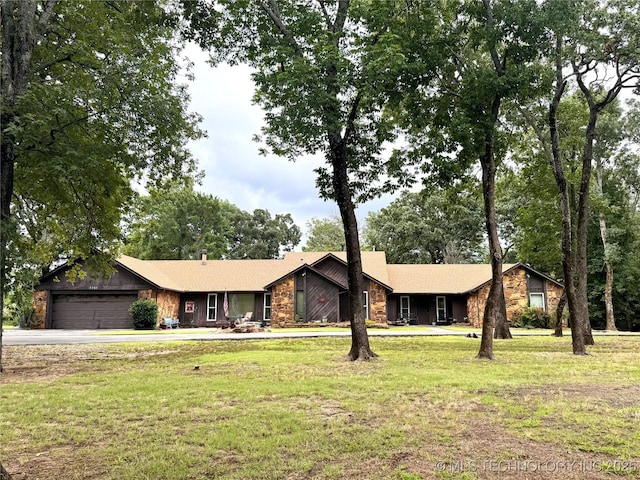 7750 River Ridge Rd, Muskogee, OK 74403 - view of front of home with stone siding, a front yard, driveway, and an attached garage