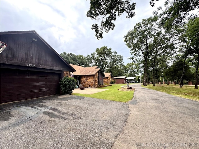 7750 River Ridge Rd, Muskogee, OK 74403 - view of front of home featuring driveway, stone siding, and a front lawn