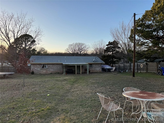 back of property featuring a lawn and fence