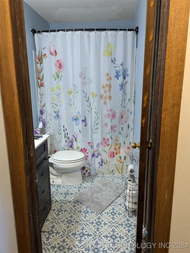 bathroom featuring toilet, vanity, a textured ceiling, and tile patterned floors