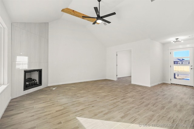 unfurnished living room featuring a large fireplace, ceiling fan, light hardwood / wood-style flooring, and vaulted ceiling