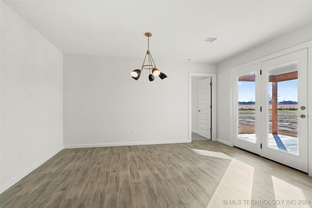 empty room featuring hardwood / wood-style floors and an inviting chandelier