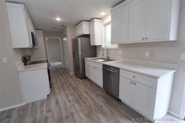 kitchen featuring sink, white cabinetry, stainless steel appliances, and light wood-type flooring