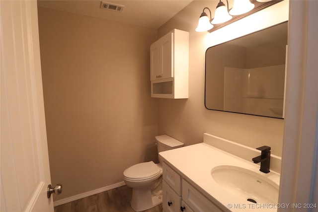 bathroom featuring hardwood / wood-style floors, vanity, toilet, and walk in shower