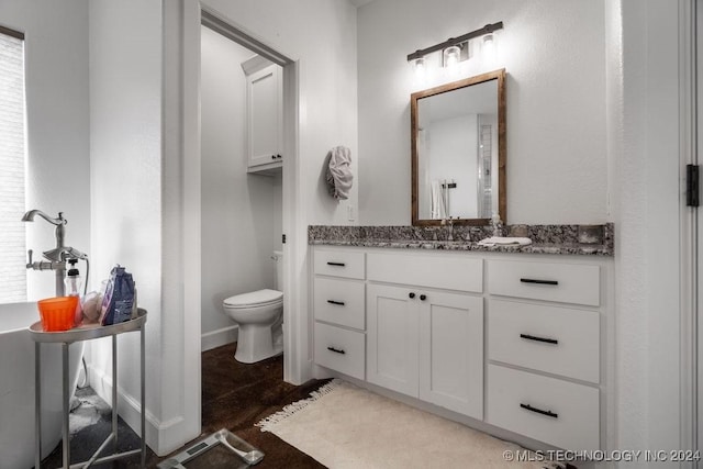 bathroom with a wealth of natural light, vanity, and toilet