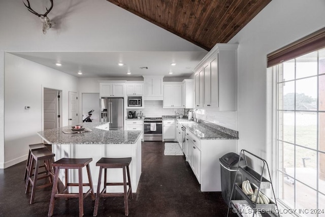 kitchen featuring a kitchen island, white cabinetry, appliances with stainless steel finishes, and vaulted ceiling