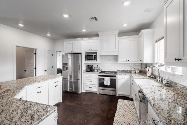 kitchen with light stone countertops, sink, stainless steel appliances, tasteful backsplash, and white cabinets