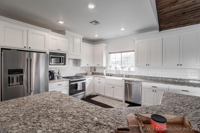 kitchen featuring sink, light stone countertops, tasteful backsplash, white cabinetry, and stainless steel appliances