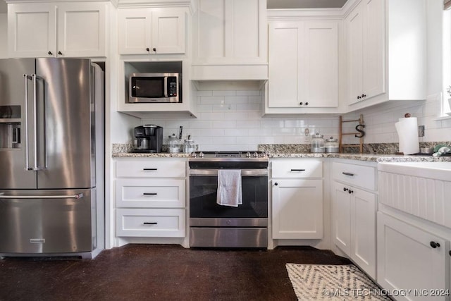 kitchen featuring backsplash, white cabinetry, light stone countertops, and appliances with stainless steel finishes