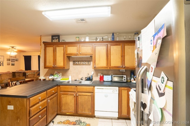 kitchen with kitchen peninsula, sink, light tile patterned floors, dishwasher, and fridge