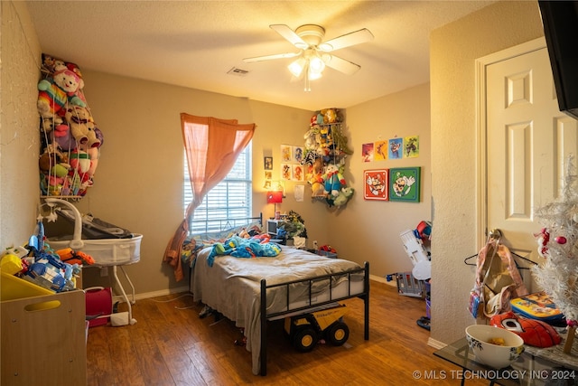 bedroom with a textured ceiling, ceiling fan, and dark wood-type flooring