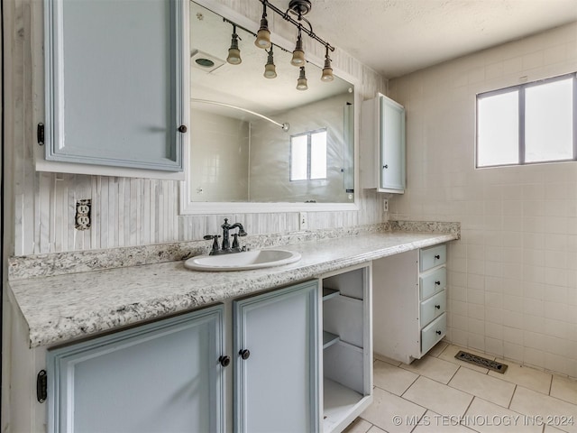 bathroom featuring a shower, tile patterned flooring, vanity, and a healthy amount of sunlight