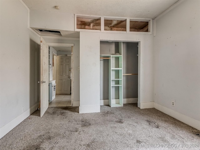 unfurnished bedroom featuring light colored carpet, ornamental molding, a textured ceiling, and a closet