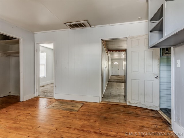 unfurnished bedroom featuring wood-type flooring, a spacious closet, a closet, and wooden walls