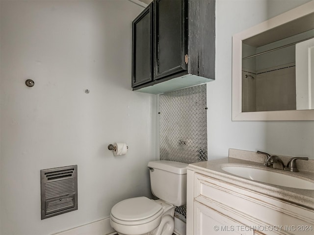 bathroom featuring heating unit, vanity, and toilet