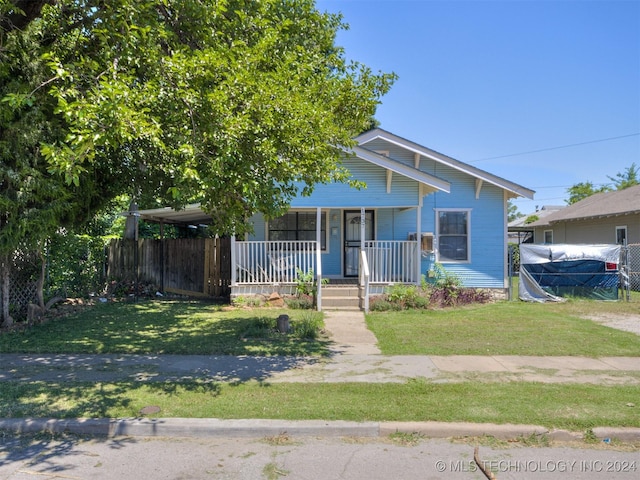 view of front facade with a front yard, a carport, and covered porch